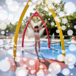 Kind spielt in einem Wasserspielplatz mit bunten Spritzdüsen und Schaumblasen